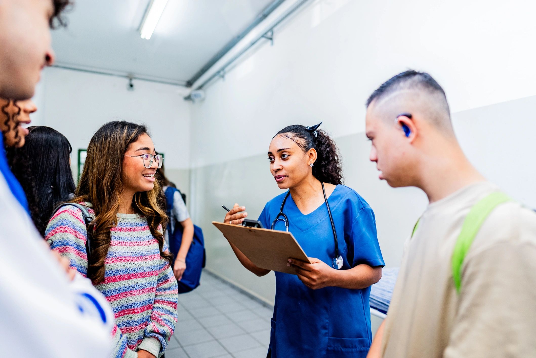 Doctor talking to and checking students before vaccination at school